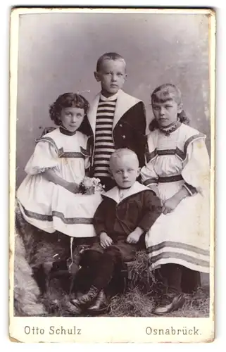 Fotografie Otto Schulz, Osnabrück, Domhof 4, Süsse Geschwister in weissen Kleidern und schwarzen Hemden sitzen beisammen
