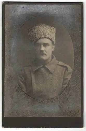 Fotografie unbekannter Fotograf und Ort, Portrait Soldat in Feldgrau mit Fellmütze, 1.WK