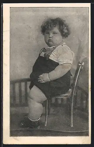 AK Kleines übergewichtiges Kind sitzt in Latzhose auf einem Stuhl