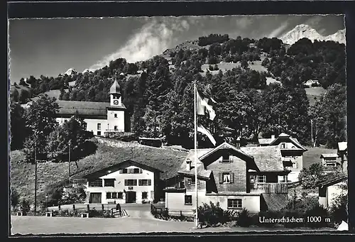 AK Unterschächen, Ortsansicht mit wehender Schweizer Flagge in den Bergen