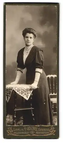 Fotografie F. Goebel, Berlin, Nollendorfstr. 37, Junge Dame mit Kreuzkette aufgestützt auf einem Tisch