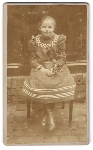 Fotografie unbekannter Fotograf und Ort, Junges Mädchen im Kleid mit Streifen auf einem Stuhl