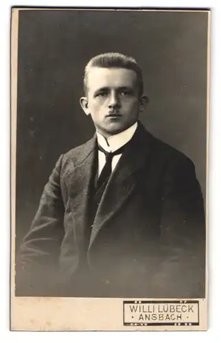 Fotografie Willi Lübeck, Ansbach, Junger Mann im dunklen Anzug mit Krawatte und aufgestelltem Kragen