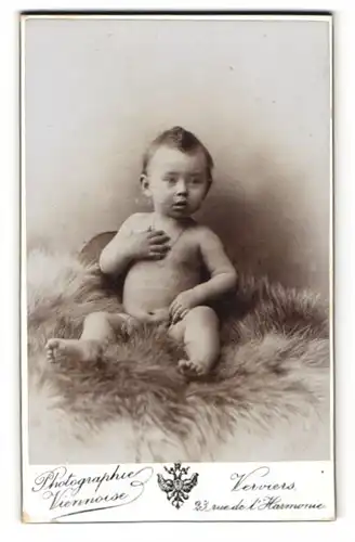Fotografie A. Wientzen, Verviers, Rue de l`Harmonie 23, Niedliches nacktes Baby mit Halskette sitzt auf einem Fell
