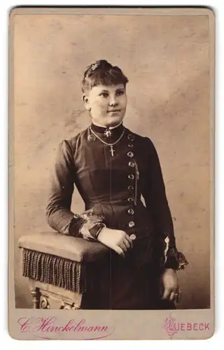 Fotografie C. Hinckelmann, Lübeck, Breitestr. 53, Schöne Dame im schwarzen geknöpften Kleid mit Kreuzkette und Brosche