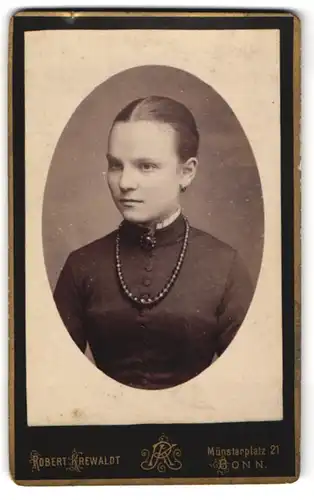Fotografie Robert Krewaldt, Bonn, Münsterplatz 21, Junge schöne Dame im schwarzen Kleid mit breiter dunkler Perlenkette