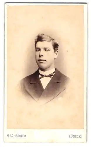 Fotografie H. Schröder, Lübeck, Beckergrube 150, Junger Bursche im dunklen Anzug mit Zierschleife und Seitenscheitel