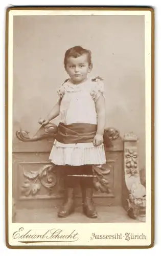 Fotografie Eduard Schucht, Aussersihl-Zürich, Casernenstr. 13, Niedliches Kleindkind im weissen Kleid mit breitem Band