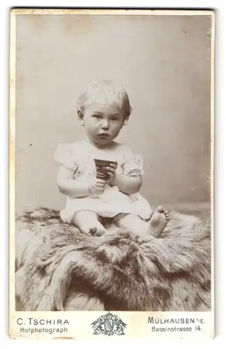 Fotografie Carl Tschira, Mülhausen, Bassinstrasse 14, Mädchen im Kleid mit Spielzeug auf einem Fell