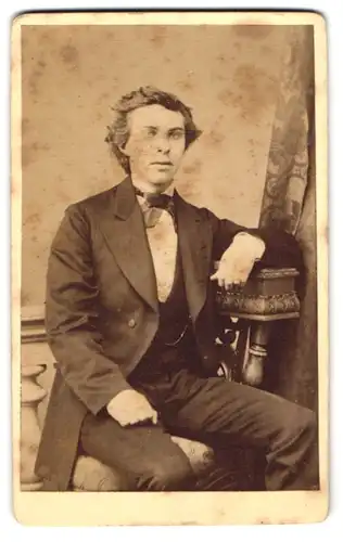 Fotografie Pr. Kahlmeyer, Osnabrück, Am Bahnhof, Junger Mann im schwarzen Anzug mit Fliege und vollen Lippen