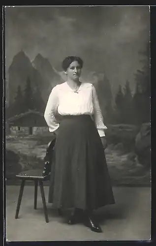 Foto-AK Frau in Bluse und Rock in einer Studiokulisse