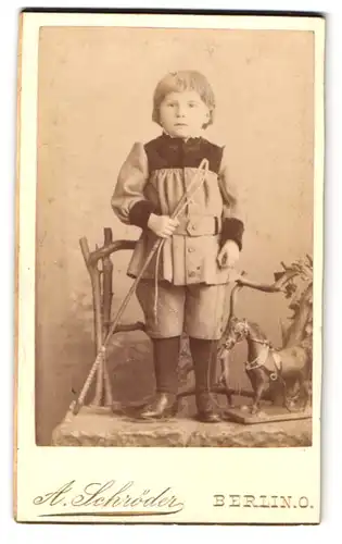 Fotografie A. Schröder, Berlin, Gr. Frankfurterstr. 117, kleiner Junge steht mit Reitpeitsche auf einem Stuhl