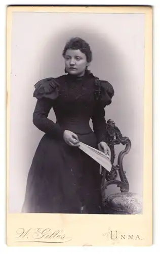 Fotografie W. Gilles, Unna, Am Bahnhof, Hübsche junge Frau im taillierten Kleid und mit Fächer