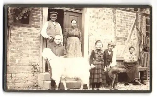 Fotografie unbekannter Fotograf und Ort, Bauernfamilie mit Ziege vor ihrem Wohnhaus, 1910