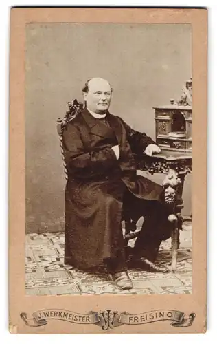 Fotografie J. Werkmeister, Freising, älterer Pastor im Mantel mit Collar sitzend am Sekretär