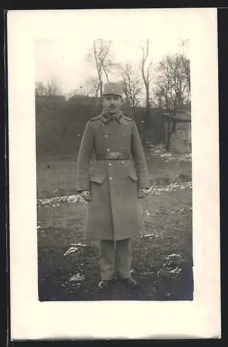 Foto-AK österreichischer Soldat in Uniform und Feldmütze mit Mantel
