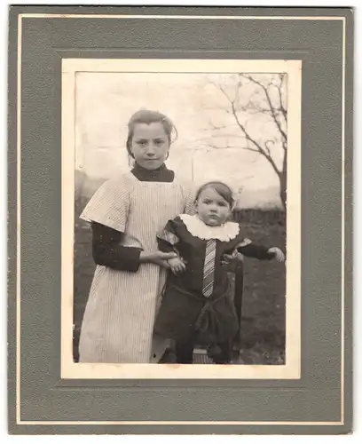 Fotografie unbekannter Fotograf und Ort, junges Mädchen mit ihrem Geschwisterkind posieren im Garten