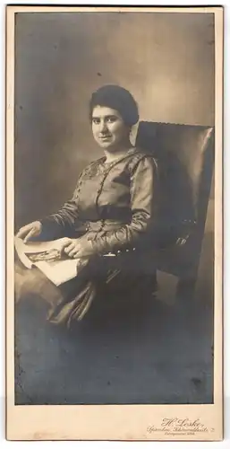 Fotografie H. Leske, Spandau, junge Frau im seidenen Kleid mit Fotobuch auf dem Schoss