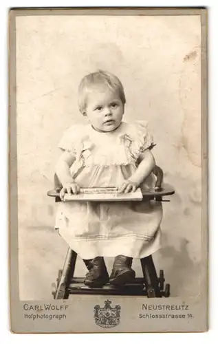 Fotografie Carl Wolff, Neustrelitz, Schlossstr. 14, Süsses Kleinkind im Kleid im Hochstuhl