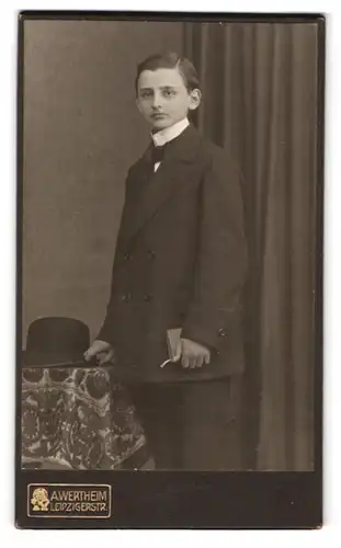 Fotografie A. Wertheim, Berlin, Leipzigerstr., Junger Mann in schlichtem Anzug mit Melone und Buch