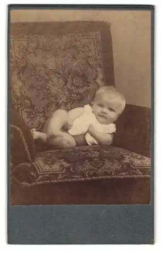 Fotografie Emil Rücker, Zehdenick, Poststr. 1, Halbnacktes Kleinkind im Hemd liegt auf einem Sessel