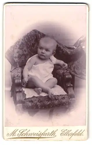 Fotografie M. Schweisfurth, Elberfeld, Herzogs-Strasse 41, Neugieriges Baby in weissem Oberteil auf einem Sessel