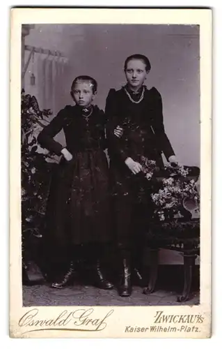 Fotografie Oswald Graf, Zwickau i. S., Kaiser Wilhelm-Platz, Zwei junge Mädchen in schwarzen Kleidern mit schönen Ketten
