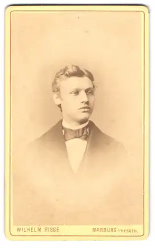 Fotografie Wilhelm Riese, Marburg i. Hessen, Junger Mann mit einer Fliege und stoischem Blick