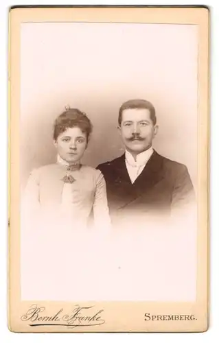 Fotografie Bernh. Franke, Spremberg, Junges Ehepaar, sie mit einer Brosche, er mit gezwirbeltem Schnurrbart