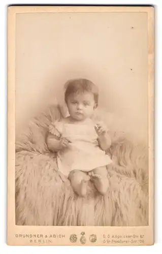 Fotografie Grundner & Abich, Berlin, Köpnicker-Str. 62, Kleines Baby im weissen Oberteil auf einem Pelz