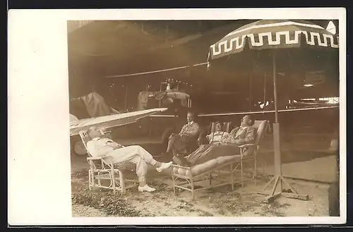 Foto-AK Piloten entspannen auf Liegestühlen vor einem Flugzeug