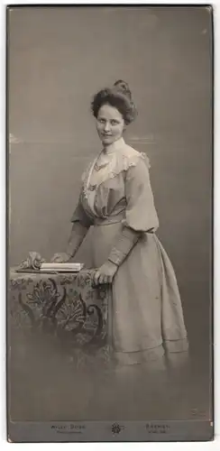 Fotografie Willy Dose, Bremen, junge Dame mit Dutt im Kleid posiert am Tisch stehend