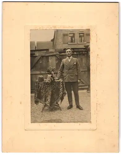 Fotografie Christ. Schwalbe, Gross-Gerau, junger hessischer Mann im Anzug mit Hut auf dem Tisch