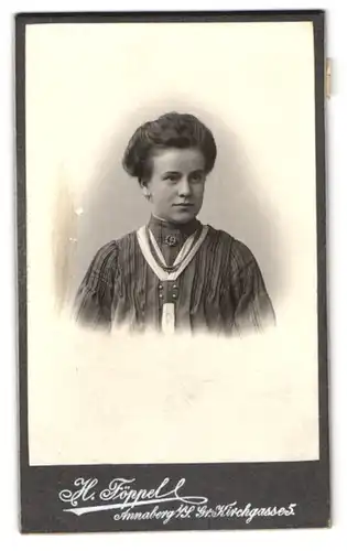 Fotografie H. Föppel, Annaberg i. S., Grosse Kirchgasse 5, Lächelnde junge Frau in gestreiftem Kleid mit Brosche