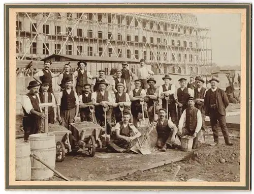 Fotografie unbekannter Fotograf und Ort, Maurer und Zimmerleute auf der Baustelle mit Schubkarren und Richtkreuz