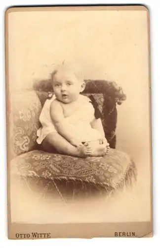 Fotografie Otto Witte, Berlin, Skalitzer-Str. 54c, Baby mit interessiertem Blick im weissen Gewand auf einem Sessel