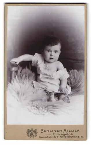 Fotografie Berliner Atelier, Mannheim, Kunststr. 12, Baby im weissen Gewand auf einem Pelz, mit erstauntem Blick