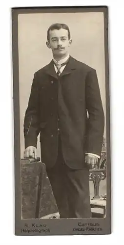 Fotografie R. Klau, Cottbus, Junger Mann mit weitem Anzug, einer Krawatte und einem Schnurrbart