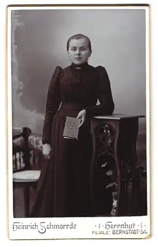 Fotografie Heinrich Schmorrde, Herrnhut, Junge Dame im taillierten schwarzen Kleid mit einem Buch in der Hand