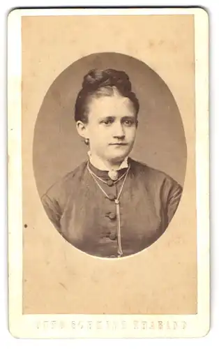 Fotografie Otto Schmidt, Tharand, Junge Dame mit elegant hochgestecktem Haar und einer Brosche am Kragen