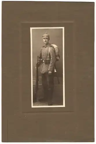 Fotografie unbekannter Fotograf und Ort, junger Soldat in Feldgrau Uniform mit Pickelhaube Tarnbezug, Ausmarschgepäck
