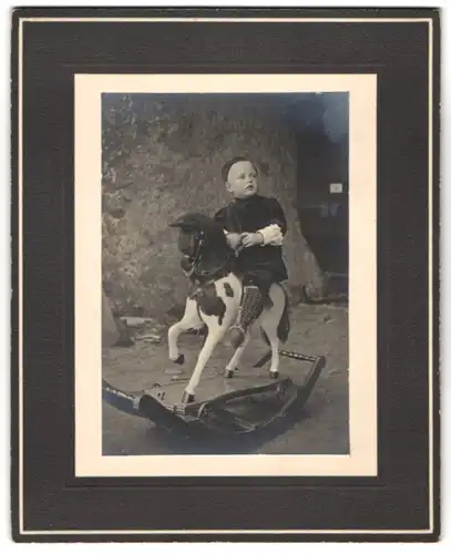Fotografie unbekannter Fotograf und Ort, niedlicher kleiner Knabe Fritz im Samtkleid auf seinem Schaukelpferd