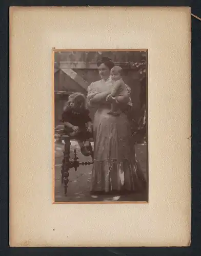 Fotografie unbekannter Fotograf und Ort, Mutter posiert mit ihren Kindern im Garten, Kleinkind auf dem Arm, Mutterglück