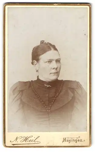 Fotografie N. Heil, Hayingen, Bürgerliche Dame im schwarzen Kleid mit stilisierten Perlen, einer Brosche und Puffärmeln