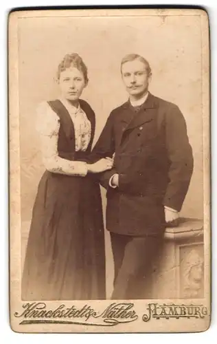 Fotografie Knackstedt & Näther, Hamburg, Gr. Bleichen 30, Junges Ehepaar mit ernstem Gesichtsausdruck, Arm in Arm