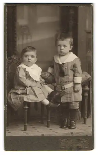 Fotografie Louis Penzel, Görlitz, Schützenstr. 3, Sitzendes Kleindkind im feinkarierten Kleid mit stehendem Bruder