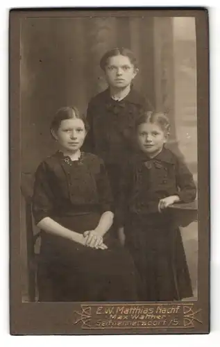 Fotografie E. W. Mattias Nachf., Seifhennersdorf i. S., Drei Schwestern in schwarzen Kleidern mit Knöpfen