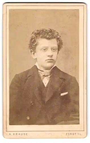 Fotografie A. Krause, Forst i. L., Pförtnerstr. 212, Junger Herr in schlichtem Anzug mit Locken u. Fliege