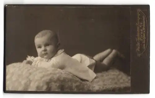 Fotografie Walter Taubmann, Pirna a. E., Grohmann- u. Jacobäerstrasse, Süsses Kleinkind in weissem Kleid auf Fell