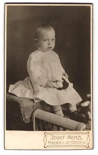 Fotografie Josef Menzl, Plauen i. V., Wettinstr. 13, Starrendes Kleinkind in weissem Kleid mit Teddy